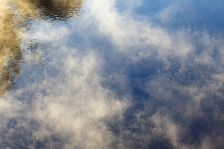 summer landscape of trees and clouds reflected in the river in the fog at dawnの写真素材