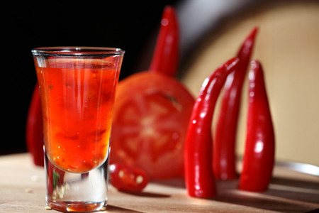 macro shot of a cocktail with tomatoes and hot peppers on a wooden boardの写真素材