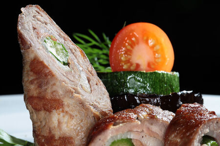 macro meatloaf with tomato sauce and zucchini on a white plate on a black background studioの写真素材