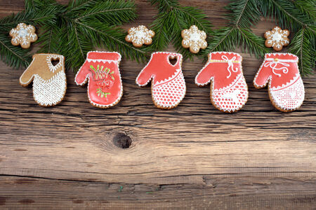 close-up still-life of of fir branches and cookies in the shape of mittens on magic Christmas holiday on background wooden boards studioの写真素材