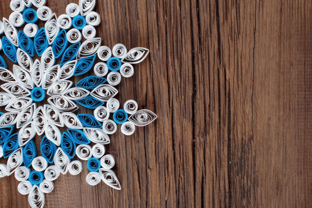 close-up of a snowflake out of paper quilling technique against the background of the old cracked board studioの写真素材