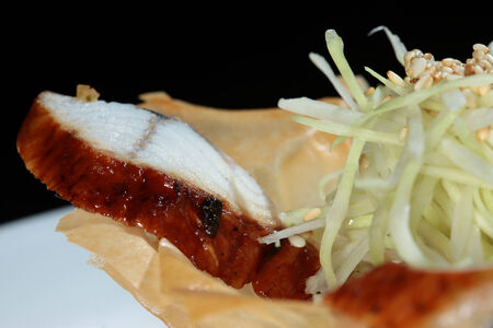 close-up gourmet salad with fish and vegetables in a basket made of dough on black studioの写真素材