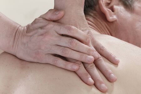 Isolated close-up of the hands of the masseur - female on man's back during a session, studioの写真素材