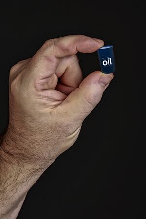 Closeup of a man holding in his hands barrels of oil on a black background studioの写真素材