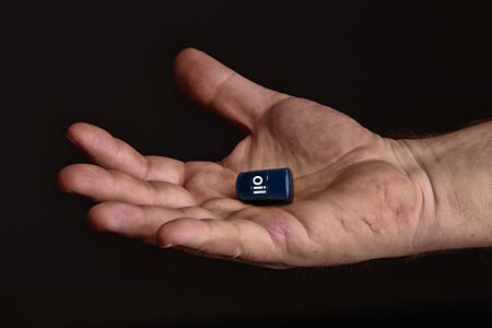 Closeup of a man holding in his hands barrels of oil on a black background studioの写真素材
