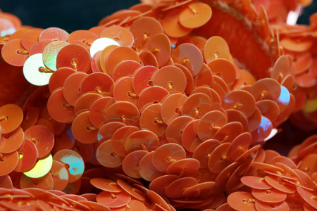 macro texture orange sequins on a dark background studio