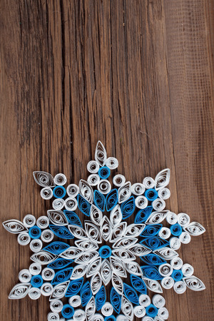 close-up of a snowflake out of paper quilling technique against the background of the old cracked board studioの写真素材
