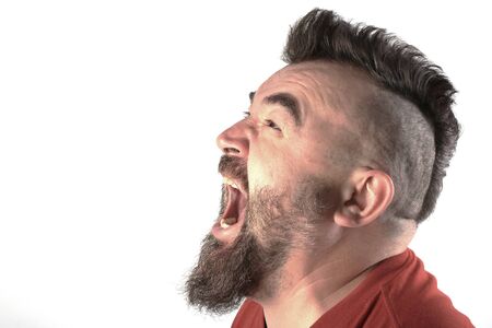close-up portrait profile of a white man with mohawk and beard screams in a angry stateの写真素材