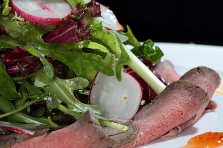 close-up elegant beautifully decorated salad tongue with vegetables and sauce on a white plateの写真素材