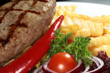 close-up of grilled cutlet with potatoes and herbs on a white plate