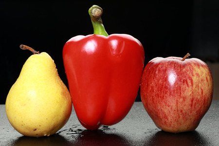 macro yellow pear, red apple and red bell peppers on black background studioの写真素材