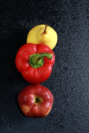 macro yellow pear, red apple and red bell peppers on black background studioの写真素材