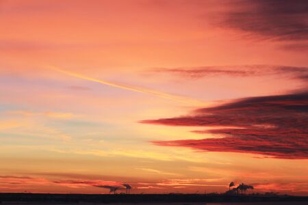 winter landscape red sunset on the ice of the river and and pipe plant on the horizon