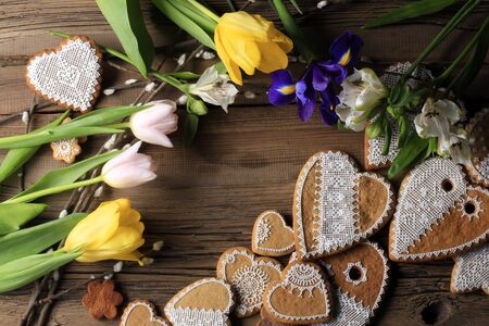macro gingerbread heart-shaped with a yellow ribbon, flowers on wood background studioの写真素材