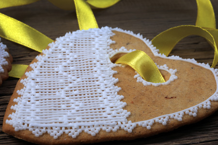 macro gingerbread heart-shaped with a yellow ribbon, flowers on wood background studioの写真素材