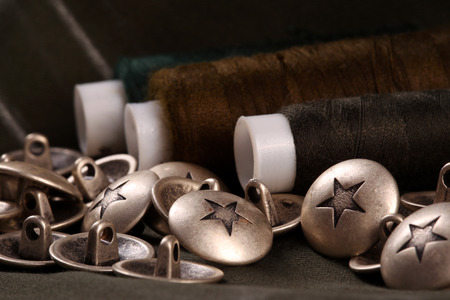 macro metal buttons with a star and spools of thread on a dark background studio