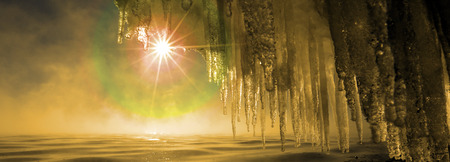 Macro bizarre of snow, ice and icicles on the rocky banks of the river in the sunshine, low angle viewの写真素材