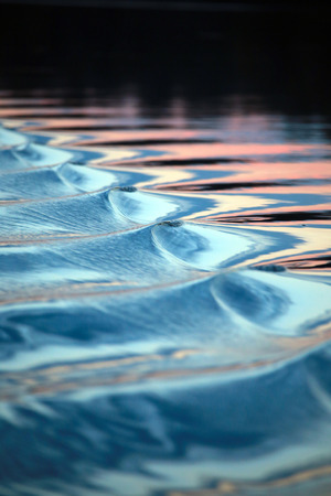 close-up amazing wavy trace of the boat on the river at sunsetの写真素材