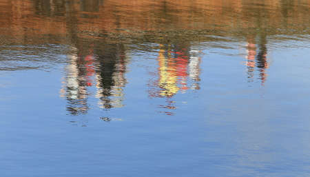 close-up reflection in the water silhouettes of people walking on a stone embankmentの写真素材