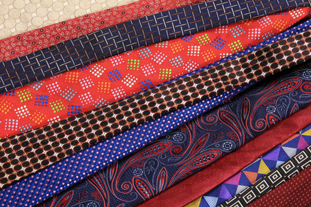 close-up of a lot of multi-colored tie against a gray flooring studio