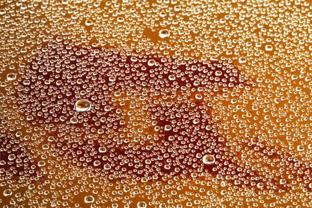 macro texture drops on the glass on the background of orange letteringの写真素材