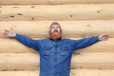 close-up portrait of a man against the backdrop of a log house in sunny spring dayの写真素材