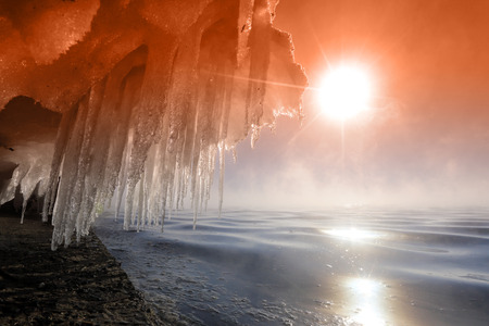 Macro bizarre of snow, ice and icicles on the rocky banks of the river in the sunshine, low angle viewの写真素材