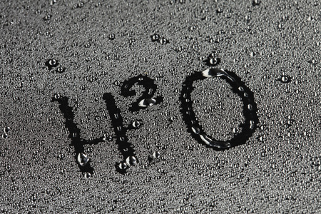 close-up texture of water drops on glass with the inscription formula H2O on a colorful backgroundの写真素材