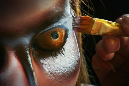 close-up portrait of a girl in a mask of an owl, body art studio on a black background