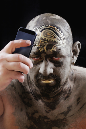 close-up bald man in a clay with ethnic pattern on the forehead on a black background Studioの写真素材