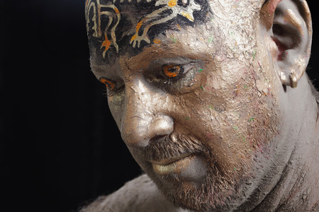 close-up bald man in a clay with ethnic pattern on the forehead on a black background Studioの写真素材