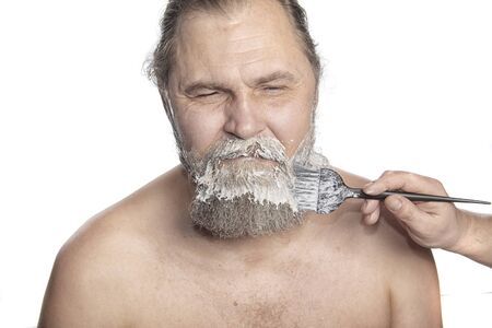 Portrait of a charismatic adult man at the time of dyeing his beard studio