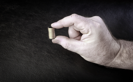 Closeup of a man holding in his hands barrels of oil on a black background studioの写真素材
