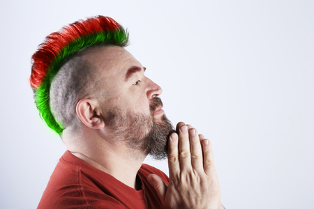 close-up portrait in profile of a man with mohawk folded his hands in prayerの写真素材