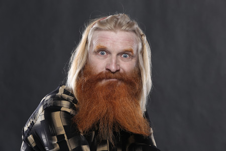 Portrait of an adult man with a red beard and mustache on a dark background studio