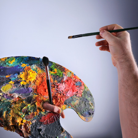 close-up isolated brush and palette in the hands of the artist's on a gray background studioの写真素材
