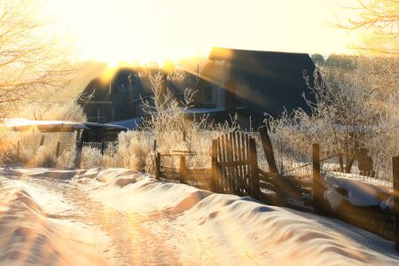 winter landscape frosty morning in the village, the frost on trees, fences and snow-covered road on...