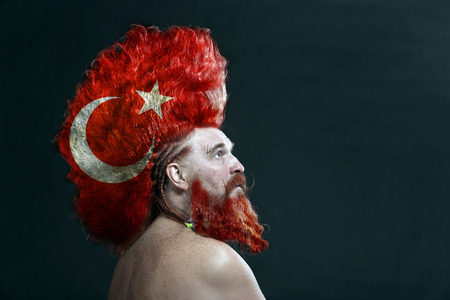 closeup portrait of a charismatic adult man with a beard and high mohawk in the studio on a dark backgroundの写真素材