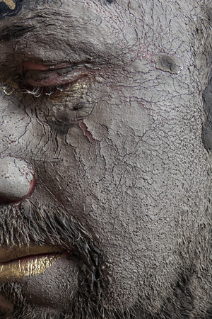 close-up portrait of a man in the clay body art , studio on a dark background