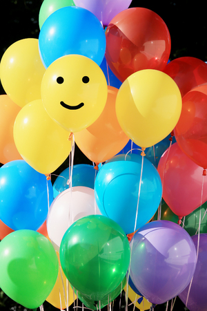 closeup of a bunch of colorful balloons on background trees in a summer parkの写真素材