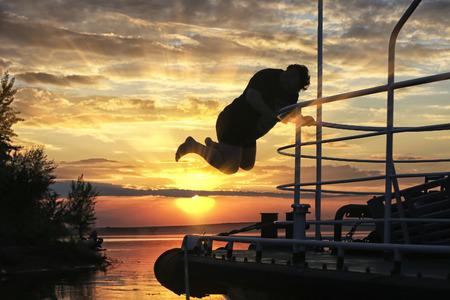 summer landscape silhouette of a man on the bow of the ship at sunsetの写真素材