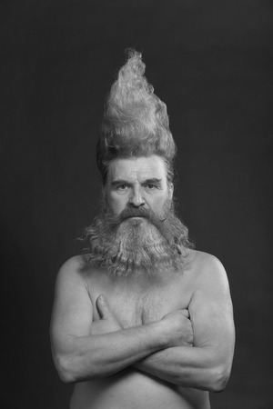 closeup portrait of a charismatic adult man with a beard and high mohawk in the studio on a gray backgroundの写真素材