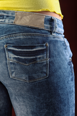 closeup women's jeans in different poses isolated on burgundy background studioの写真素材