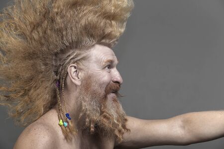closeup portrait of a charismatic adult man with a beard and high mohawk in the studio on a gray backgroundの写真素材