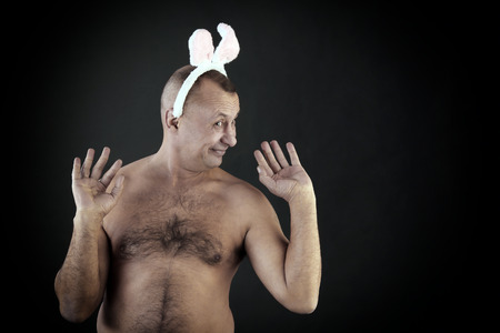 funny portrait of a man with a pink rabbit ears on gray background studio