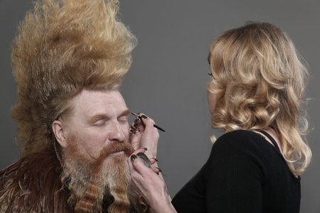 closeup hair stylist working with a man over the way a rooster on a gray background studioの写真素材