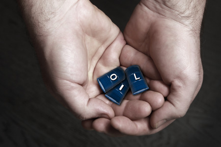 Closeup of a man holding in his hands barrels of oil on a black background studioの写真素材