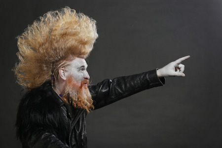 closeup portrait adult biker in black leather jackets and high mohawk and beard on a gray background の写真素材