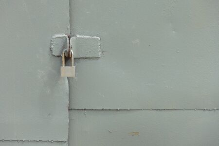 grey metal padlock on grey metal garage gatesの写真素材