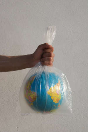Hand holding a plastic bag with a world globe. Save earth concept.